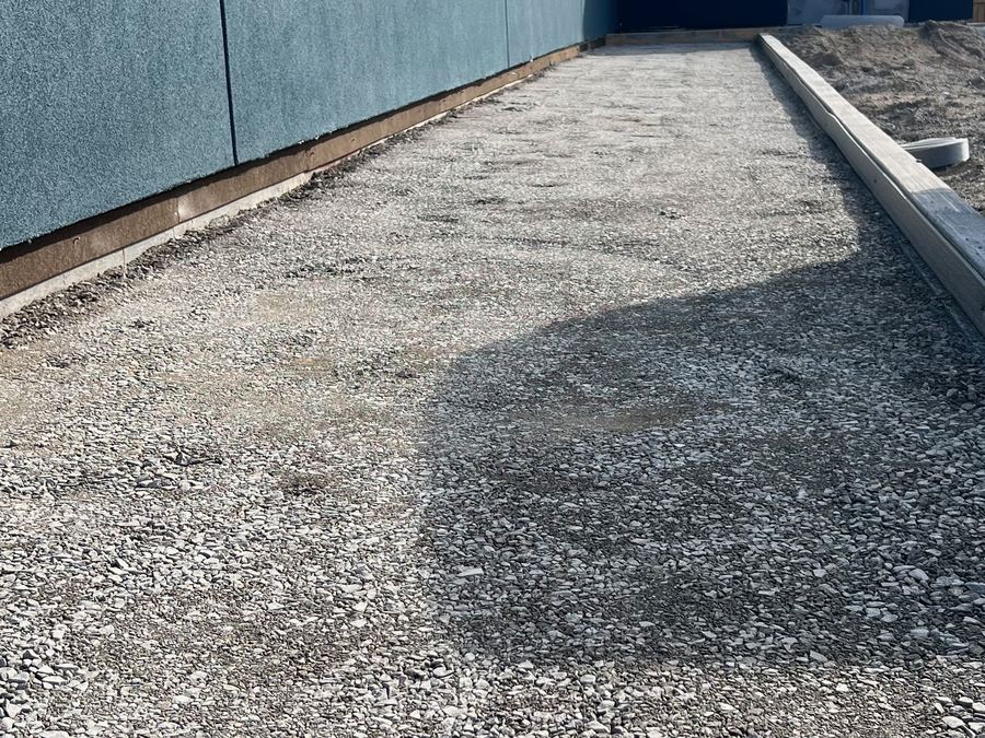 Graded gravel base and new curb beside a retail building